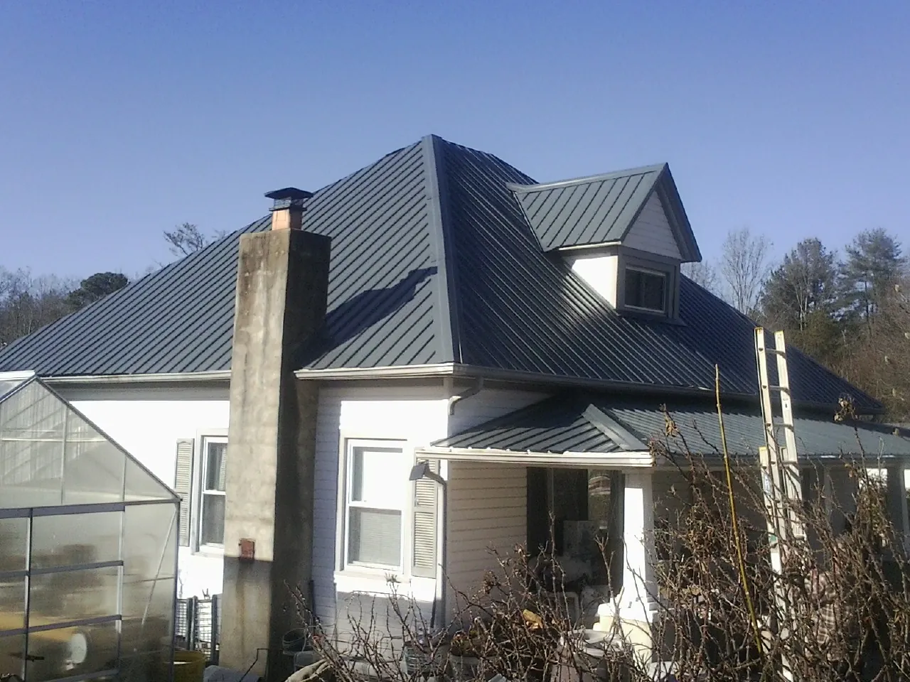 Dark blue standing seam metal roof on a white farmhouse with dormer — Slate & Tile Roof Repair by Roofing Brothers in Blythe
