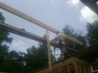 Carpenter setting a ridge beam over a new addition frame — Ice Dam Removal by Roofing Brothers in Blythe