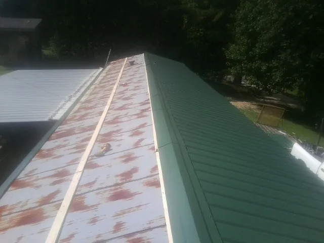 Old rusted panels beside newly installed green metal roofing — Wind Damage Roof Repair by Roofing Brothers in Blythe