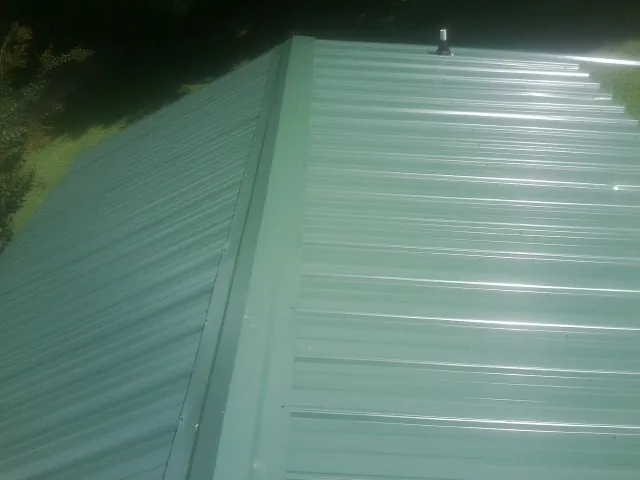 New green metal panels meeting at the ridge of a roof — Flat Roof Repair work by our crew in Blythe