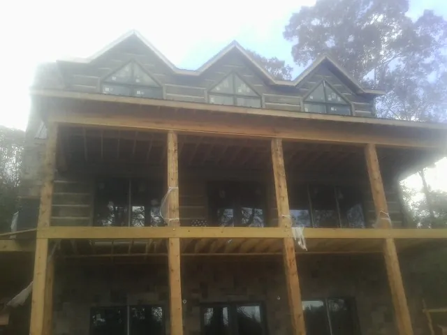 Dormers and porch framing on a large log home under construction — Roof Coating work by our crew in Blythe
