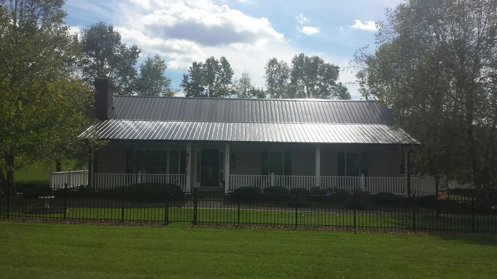 Gray metal roof on a brick ranch with a full width front porch — Gutter Guard Installation work by our crew in Blythe