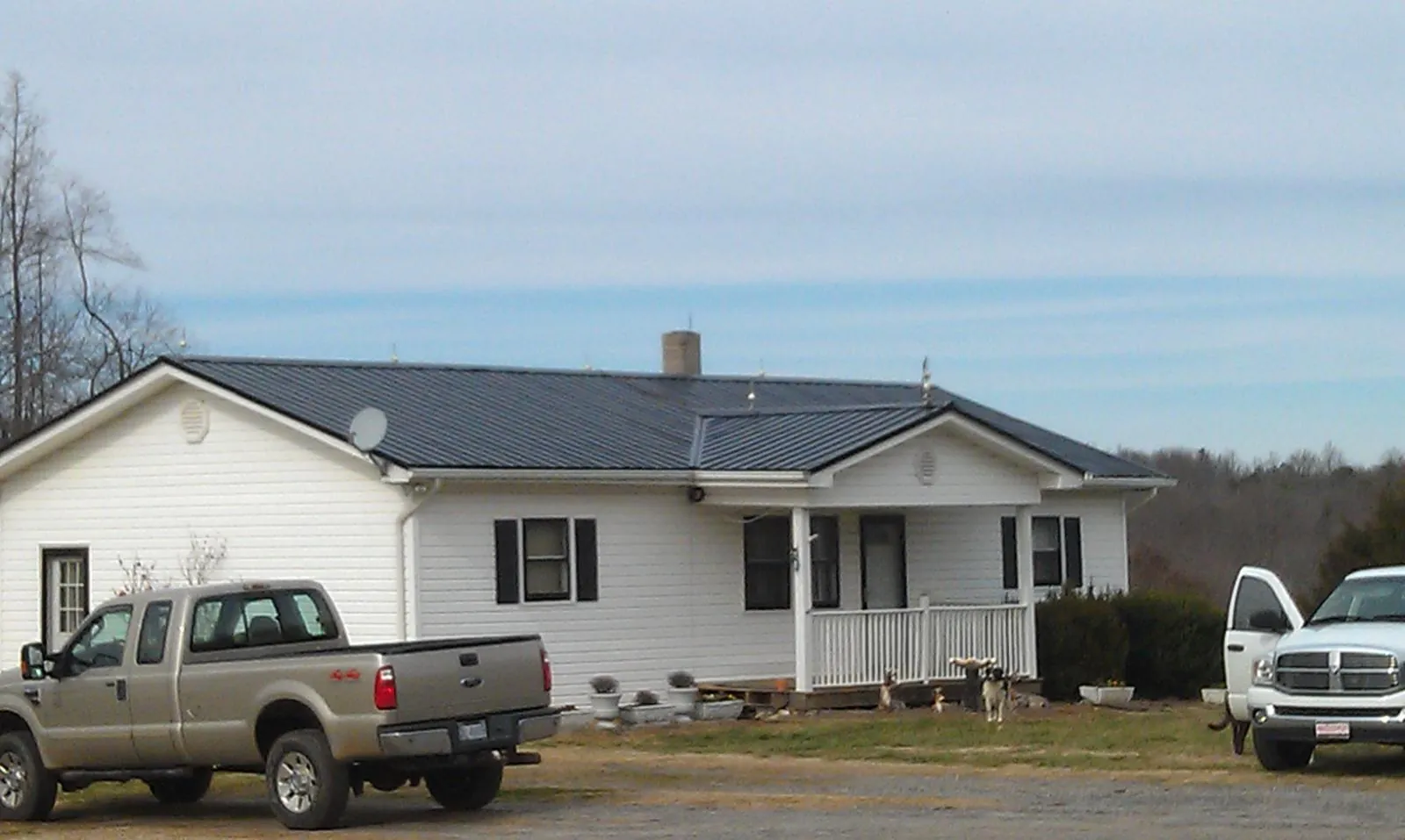 Finished dark metal roof on a white ranch home with work trucks parked in Blythe