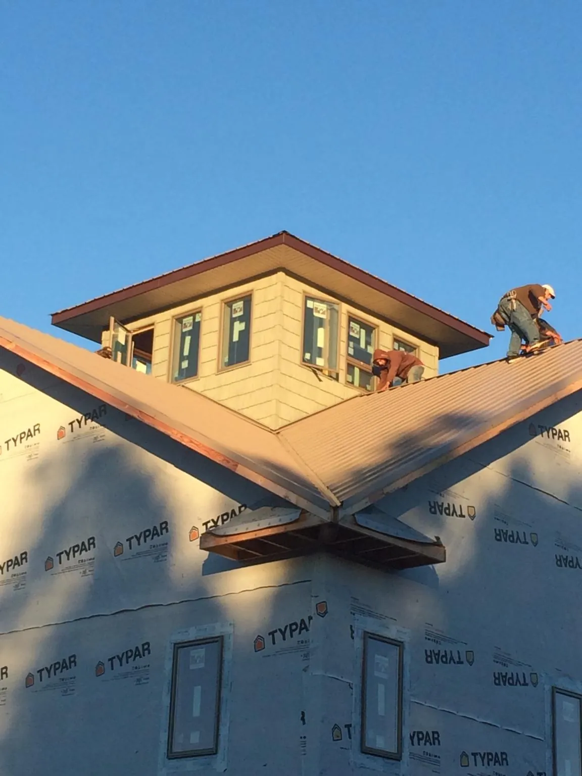 Roofers working around a rooftop cupola on a new metal roof at sunset — Roof Waterproofing in Blythe by Roofing Brothers